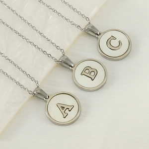 Minimalist stainless steel necklaces with A B C shell pendants on beige fabric