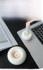 Minimalist white ceramic doughnut candle holder set on a black table with a laptop