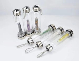 Detail view of six glass energy water bottles with natural healing crystal gravel chambers