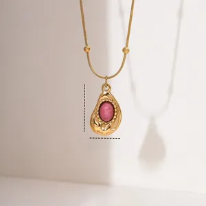Macro detail of teardrop rhodochrosite pendant on gold stainless steel snake chain