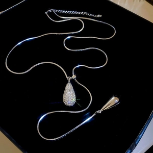 Close-up of sparkling rhinestone teardrop pendant on a silver-tone snake chain necklace
