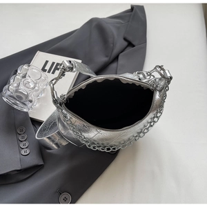 Detail of silver metallic dumpling bag with chain strap and zipper on grey blazer