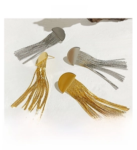 Détail de boucles d'oreilles polies avec pampilles dorées et argentées élégantes