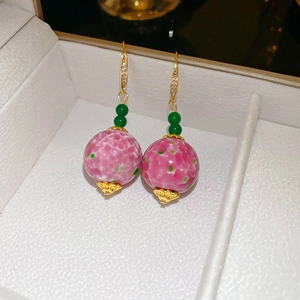 Detail of pink floral ceramic earrings with green beads and gold cubic zirconia hooks