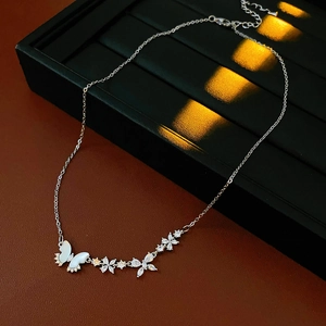 Gros plan d'un collier papillon en argent avec zircone sur un plateau de présentation