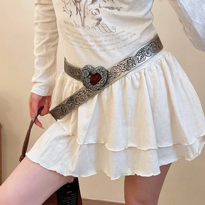 Close-up of vintage silver belt featuring engraved floral patterns and a red heart buckle
