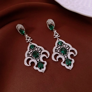 Détail de boucles d'oreilles vintage en forme d'arbre avec gemmes vertes et strass blancs