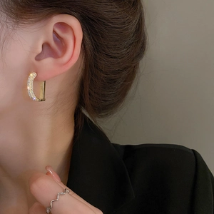 Close-up of gold-plated D-shaped earrings with sparkling cubic zirconia on model
