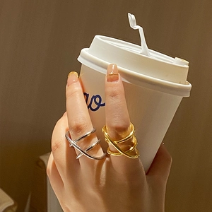 Close-up of stacked gold and silver multilayer crisscross rings on a hand holding a cup