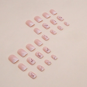 Short square pink ombre press-on nails with white flower designs for a sweet manicure