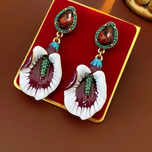 Macro detail of vintage floral drop earrings with red crystal and purple enamel finish
