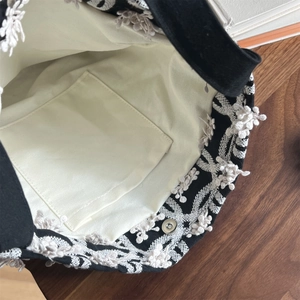 Detailansicht einer schwarzen Canvas-Tasche mit Blumenstickerei und Magnetverschluss