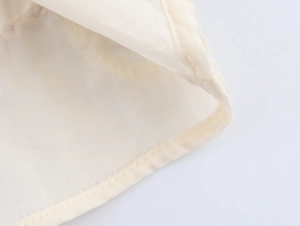 Close-up of high-quality sewing stitches on cream-white cotton linen embroidered shirt