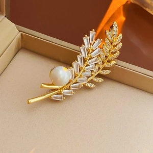 Macro shot of gold plated leaf brooch with pearl and cubic zirconia in a jewelry box