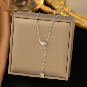 Detailed close-up of a silver bean pendant necklace draped over a premium jewelry box