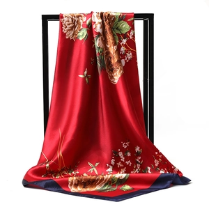 Detail of red floral satin scarf with navy border hanging on a display stand