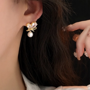Gros plan d'une boucle d'oreille nœud en zircon et perle portée avec élégance