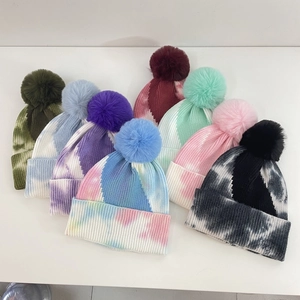 Tie-dye knit winter beanie hats with faux fur pom poms in various gradient colors