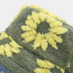 Close-up of soft gray-green plush fabric with yellow sunflower embroidery detail