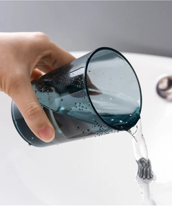 Détail d'un gobelet bleu foncé translucide montrant l'eau coulant du bord du verre