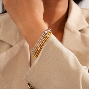 Detail of gold and silver plated cutout bracelets with zircons on a model's wrist