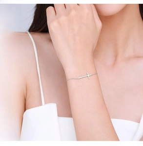 Detail of minimalist S925 sterling silver cross bracelet on woman's wrist