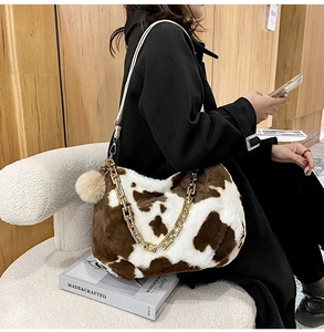 Detail of plush faux fur tote with brown cow print, gold chain, and white leather strap