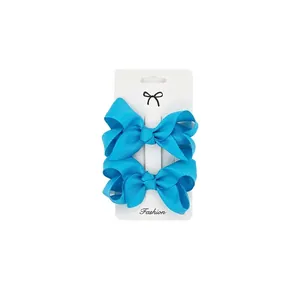 Detail of blue grosgrain ribbon bow hair clips on white retail display card