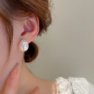 Gros plan d'un mannequin portant une boucle d'oreille perle sirène ovale iridescente