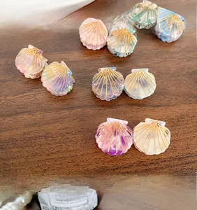 Macro view of shell-shaped acetate hair claws with marble texture and gold ray accents