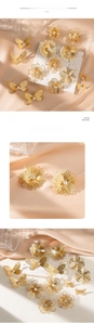 Macro view of gold butterfly and flower earrings with rhinestones on silk