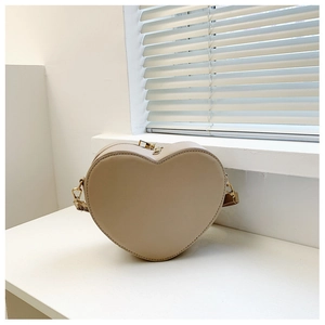 Dettaglio della borsa a tracolla color crema a forma di cuore con eleganti zip dorate