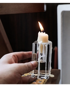 Close-up of a minimalist clear glass candle holder with candle wax dripping on the surface