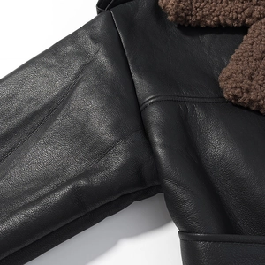 Detailed close-up of stitching on black leather jacket with brown faux fur collar lining