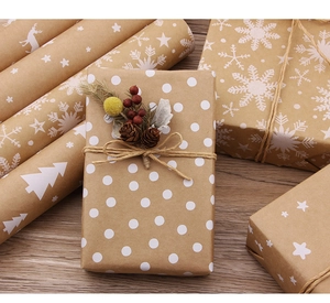 Detail of kraft Christmas wrapping paper featuring white snowflakes and reindeer prints