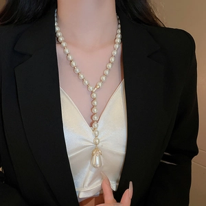 Close-up of Y-shaped pearl necklace with large pendant on a model in professional attire