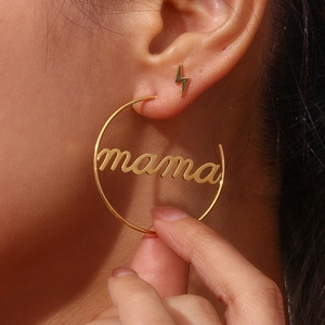 Close-up of gold hoop earrings with mama script and lightning bolt studs on model