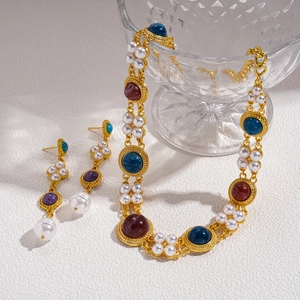 Baroque style jewelry set with gold necklace and pearl earrings on a white surface