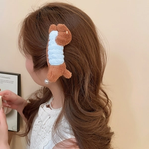 Detailed view of a plush brown puppy hair clip worn on model's wavy hair