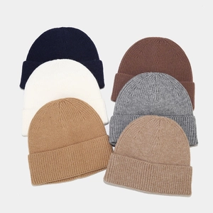 Stack of ribbed knit beanies in navy, cream, caramel, brown, grey and oat colors