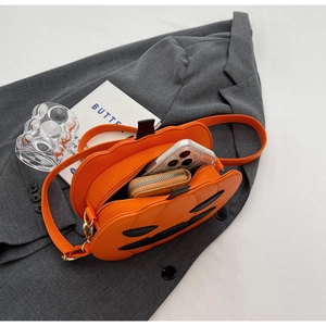 Top-down view of an orange pumpkin crossbody bag with a black jack-o'-lantern face