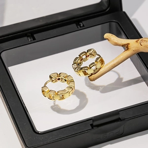Détails de boucles d'oreilles dorées géométriques dans un cadre flottant noir
