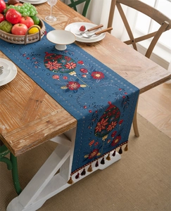 Blue Christmas table runner with red festive ornaments, floral patterns, and elegant tassels