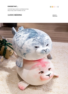 Close-up of soft grey and pink plush seal pillows on a cozy rug with gift box