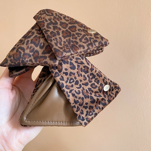 Macro shot of triangular leopard print hair claw with golden snap button and brown leather