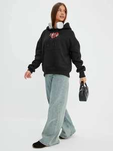 Λεπτομέρεια μαύρου oversized hoodie με τύπωμα σπασμένης καρδιάς και τσέπη καγκουρό