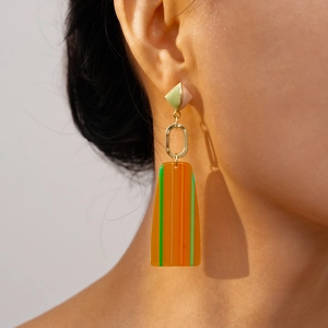 Detail view of resin earrings with geometric color-block shapes and colorful stripe patterns