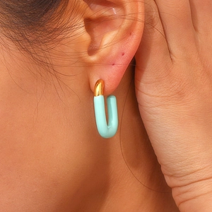 Detail of 18K gold-plated U-shaped earring with mint green lacquer on a model's ear