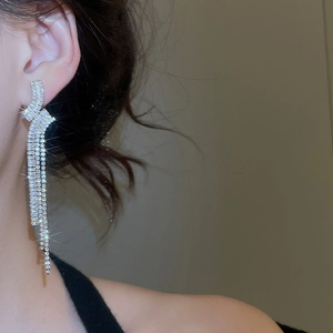 Dettaglio di orecchini a nappa in argento con zirconi indossati da una modella in posa