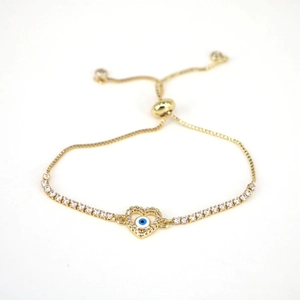 Detail of adjustable gold heart bracelet with evil eye motif and white cubic zirconia